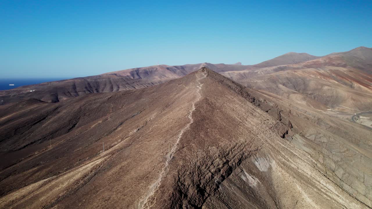 Paesaggio arido e ondulato di Fuerteventura con montagne e cielo azzurro limpido, vista aerea