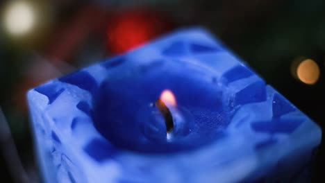 a burning blue candle swirled in a christmas wreath