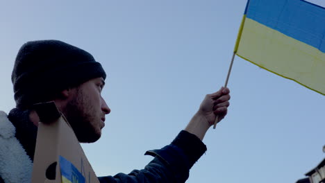 Activista-Ondeando-La-Bandera-Ucraniana-En-Protesta-En-Praga,-Pájaro-Volando-Sobre