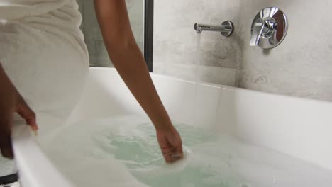 Midsection-of-african-american-woman-preparing-bath-in-bathroom