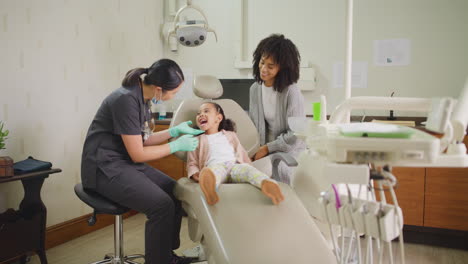 dentist examining little girls mouth during dental