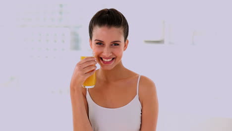 una mujer hermosa y alegre disfrutando del jugo de naranja.