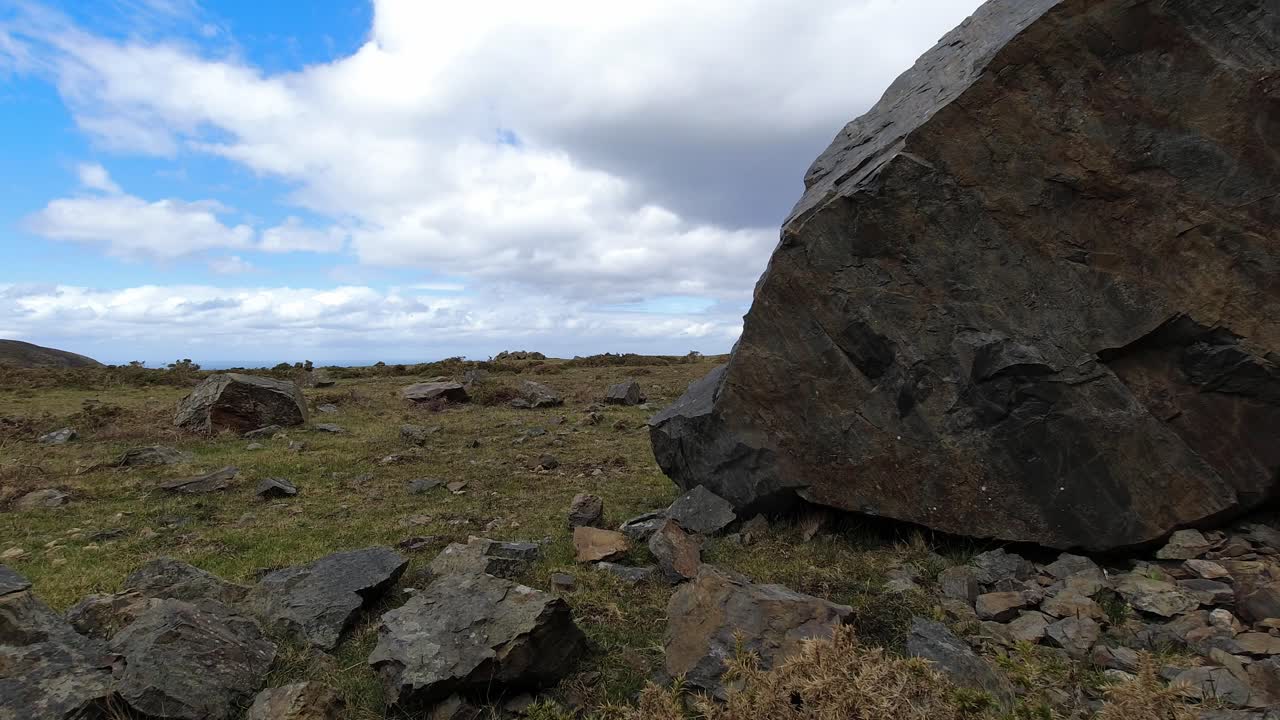 비 폭풍우 날씨가 지나감에 따라 돌이 많은 잔디 산 꼭대기 시간 경과에 거대한 바위