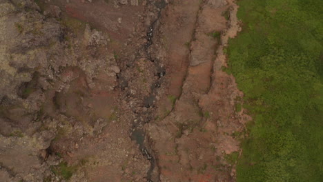 corriente de agua serpenteando a través del cañón en los fiordos del oeste de islandia, toma aérea de drones