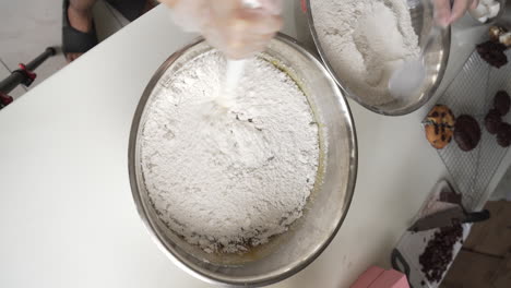 pastry chef adding and mixing flour into dough mixture