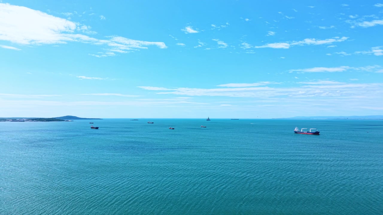 海の青い水面に浮かぶボート。雲の少ない澄んだ空の下、複数のボートが青い水面に浮かび、広大な海の景色が広がっている。