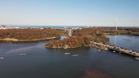 aerial footage of multiple rowers in competition emerging from underneath road bridge