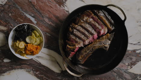 top-down shot of a ribeye steak being plated into a cast iron pan