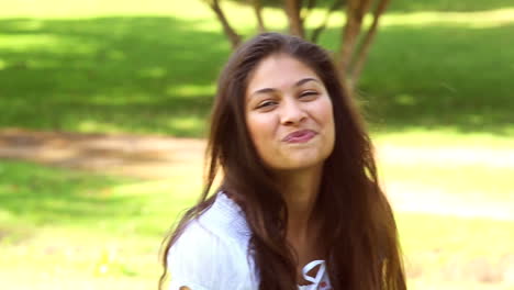 una chica bonita sentada en la hierba sonriendo a la cámara
