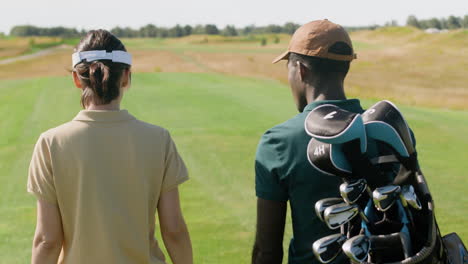 caucasian woman and african american man meeting on the golf course.