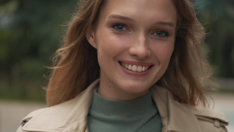 caucasian woman looking at the camera and smiling outdoors.