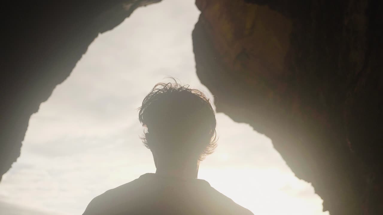 A man walking out to the beautiful bright sunlight from a dark cave in Madeira, Portugal - Slow motion