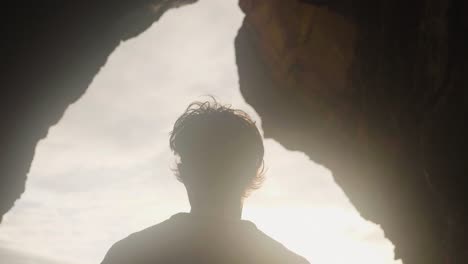 a man walking out to the beautiful bright sunlight from a dark cave in madeira, portugal - slow motion