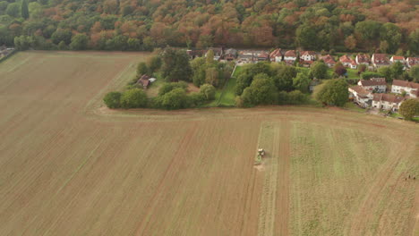 stationary aerial shot of a tractor ploughing a large field