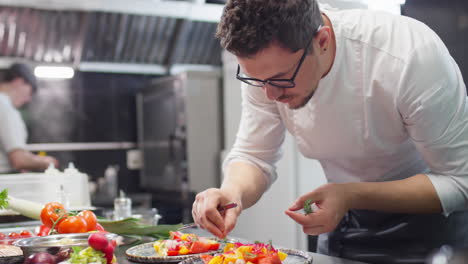 chef adding garnish to tomato salad in restaurant kitchen