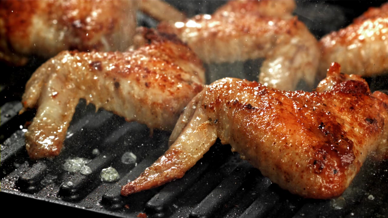 Deliziose alette di pollo che grigliano e sfrigolano su una piastra calda