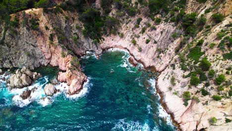 tossa de mar, costa brava, catalonia, spain - a tranquil scene of turquoise water crashing against the rugged, steep sea cliffs - high angle shot