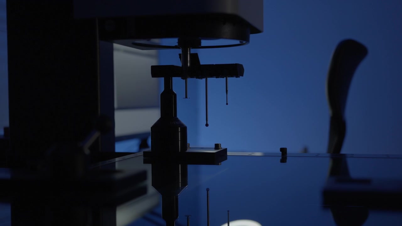 Optical inspection machine selecting a measuring probe before performing dimensional analysis on a CNC machined metal part.