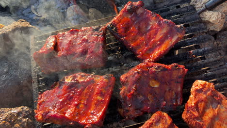 Kochen-Saftiger-Schweinerippchen-Vom-Grill-Auf-Einem-Feuergrill-Im-Freien-Mit-Rauch-Und-Asche,-Leckeres-Essen,-4K-Aufnahme