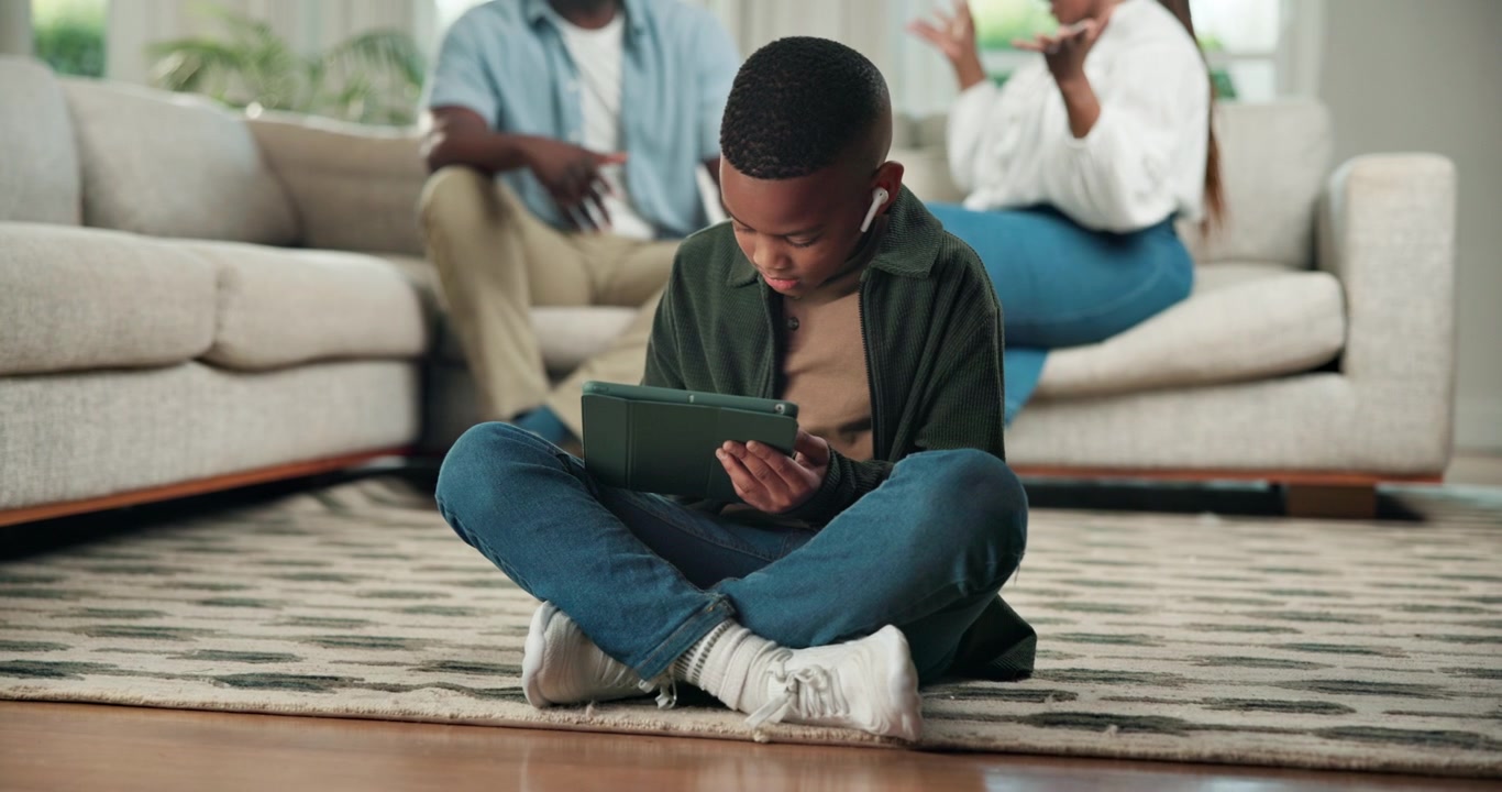 Young Boy Using Tablet While Parents Talk in Background