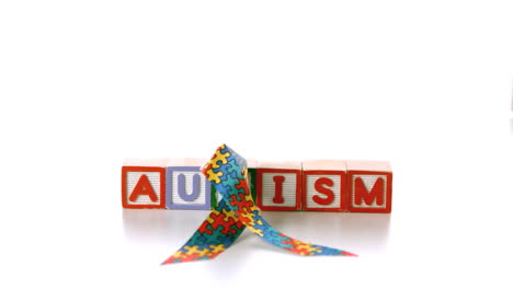 cinta de conciencia que cae sobre bloques que escriben autismo sobre un fondo blanco