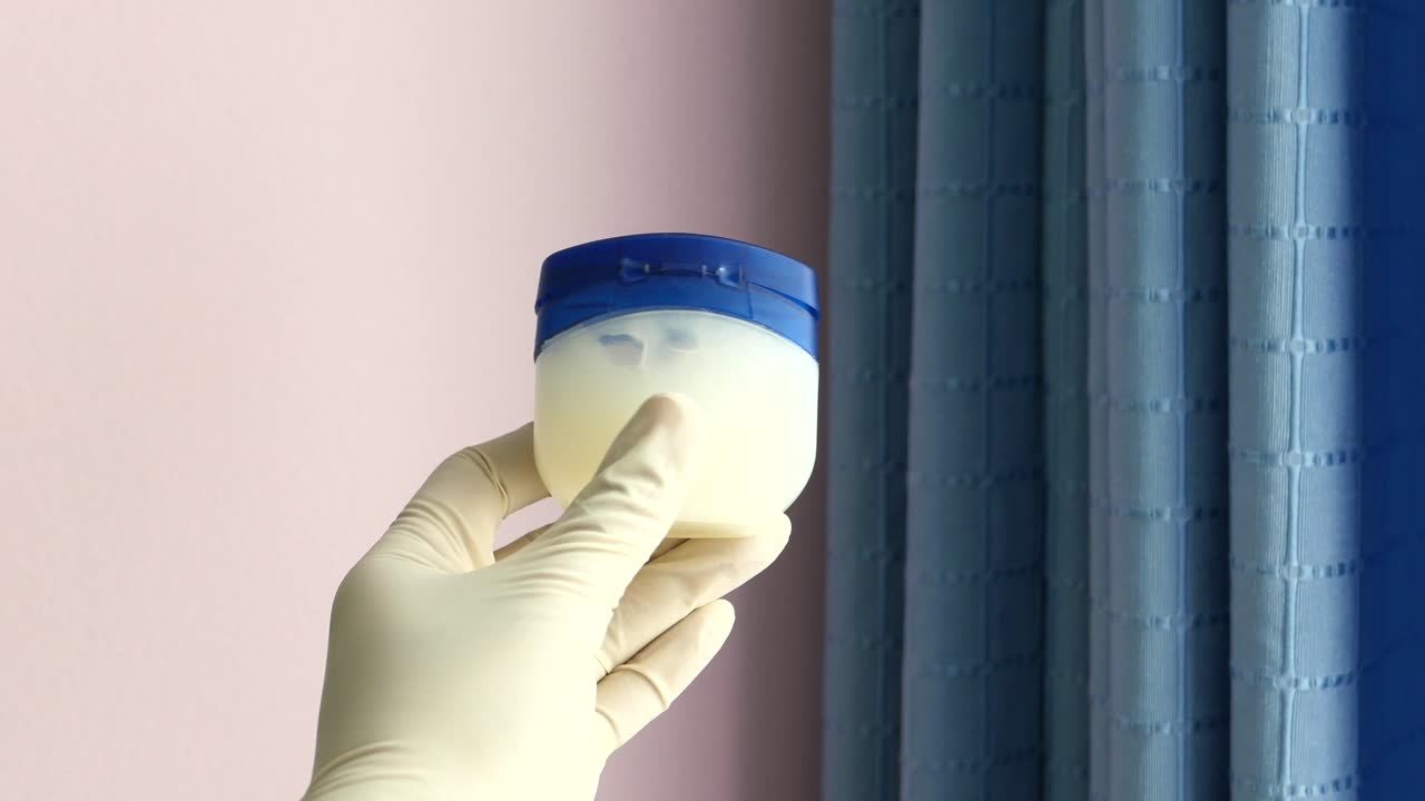 mano sosteniendo un pequeño frasco de plástico de crema