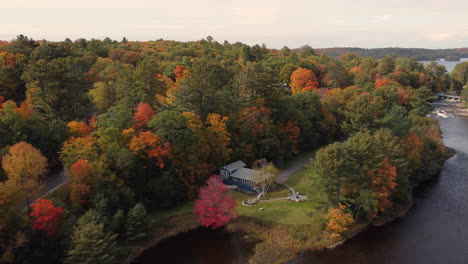 villas a orillas del río con densos árboles otoñales cerca del parque provincial algonquin, región de muskoka, ontario, canadá