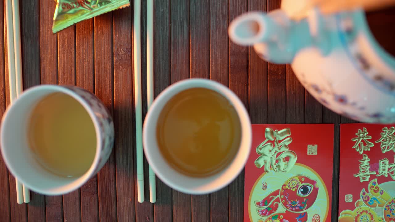 赤い封筒が置かれた場所で、伝統的な中国茶をカップに注いでいる手