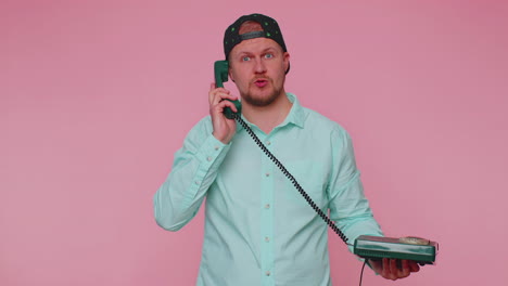 Cheerful-tourist-man-secretary-talking-on-wired-vintage-telephone-of-80s,-says-hey-you-call-me-back