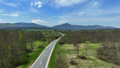 aerial shot of a road that stretches across a mountain plateau overgrown with grass and groves