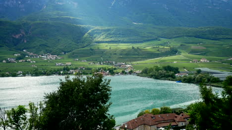 colorful reflected kalterer lake in italy with beautiful rural landscape in background during sunny day in italy