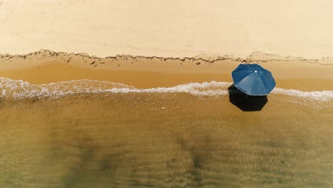 Drohnenansicht-Von-Oben-Nach-Unten-Auf-Einen-Einsamen-Sonnenschirm-An-Einem-Einsamen-Orangefarbenen-Sandstrand