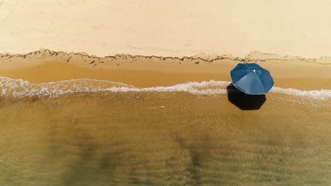 vista aérea de arriba hacia abajo de drones de solitaria sombrilla en una playa desierta de arena naranja