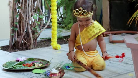 adorable bebé vestido como el dios hindú krishna linda expresión facial con flauta en janmashtami