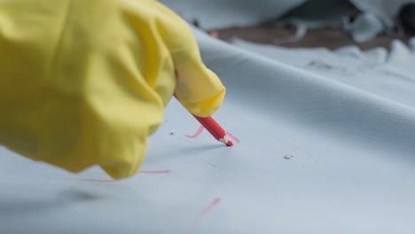 trabajador textil escribiendo en una piel de animal con un lápiz de marca de cera roja en una fábrica de cuero