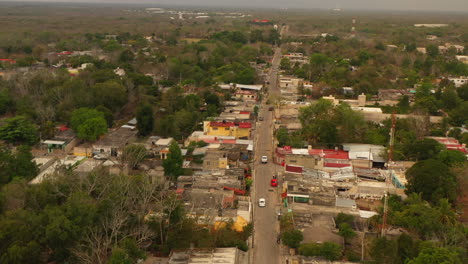 Aerial-view-of-cars-driving-on-street-in-poor-suburban.-Low-one-floor-buildings-in-town.-Valladolid,-Mexico