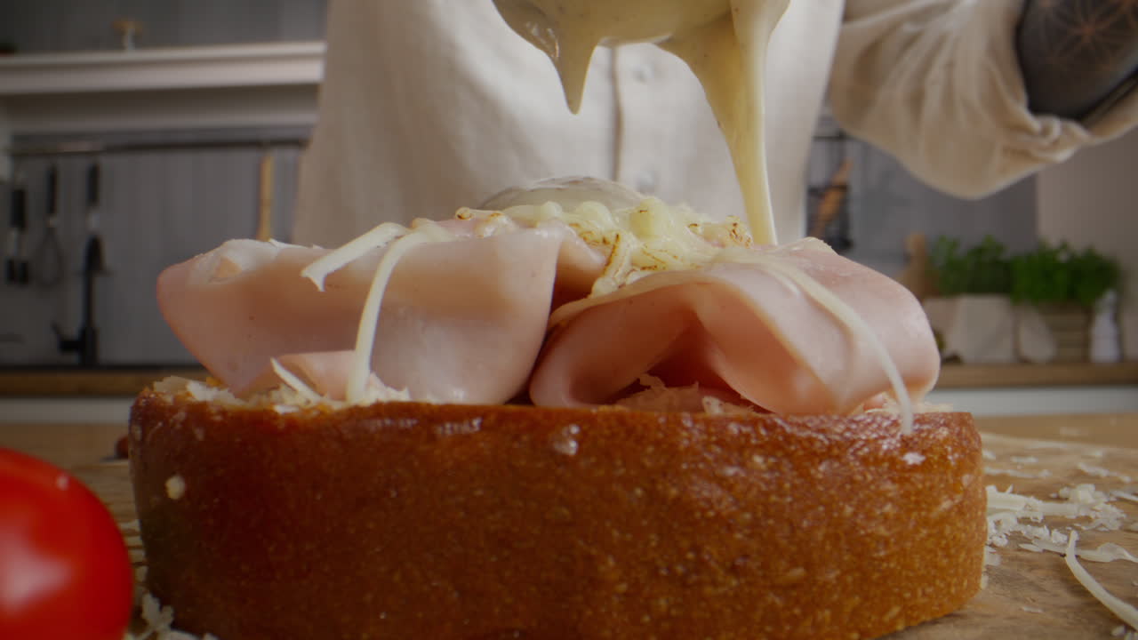 Chef Preparing a Gourmet Ham and Cheese Sandwich with Sauce