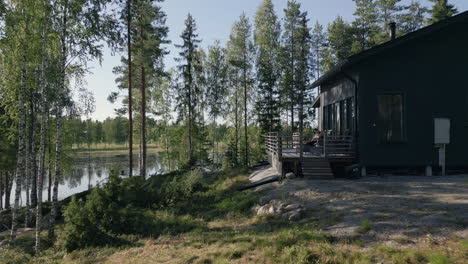 cabin by a peaceful lakeside surrounded by tall trees on a sunny day in the forest