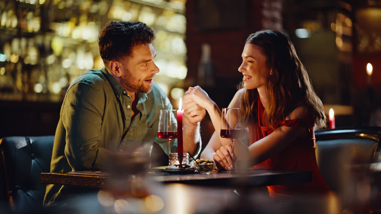 Primo piano di un uomo affettuoso che prende la mano di una donna dichiarandole il suo amore in un ristorante accogliente