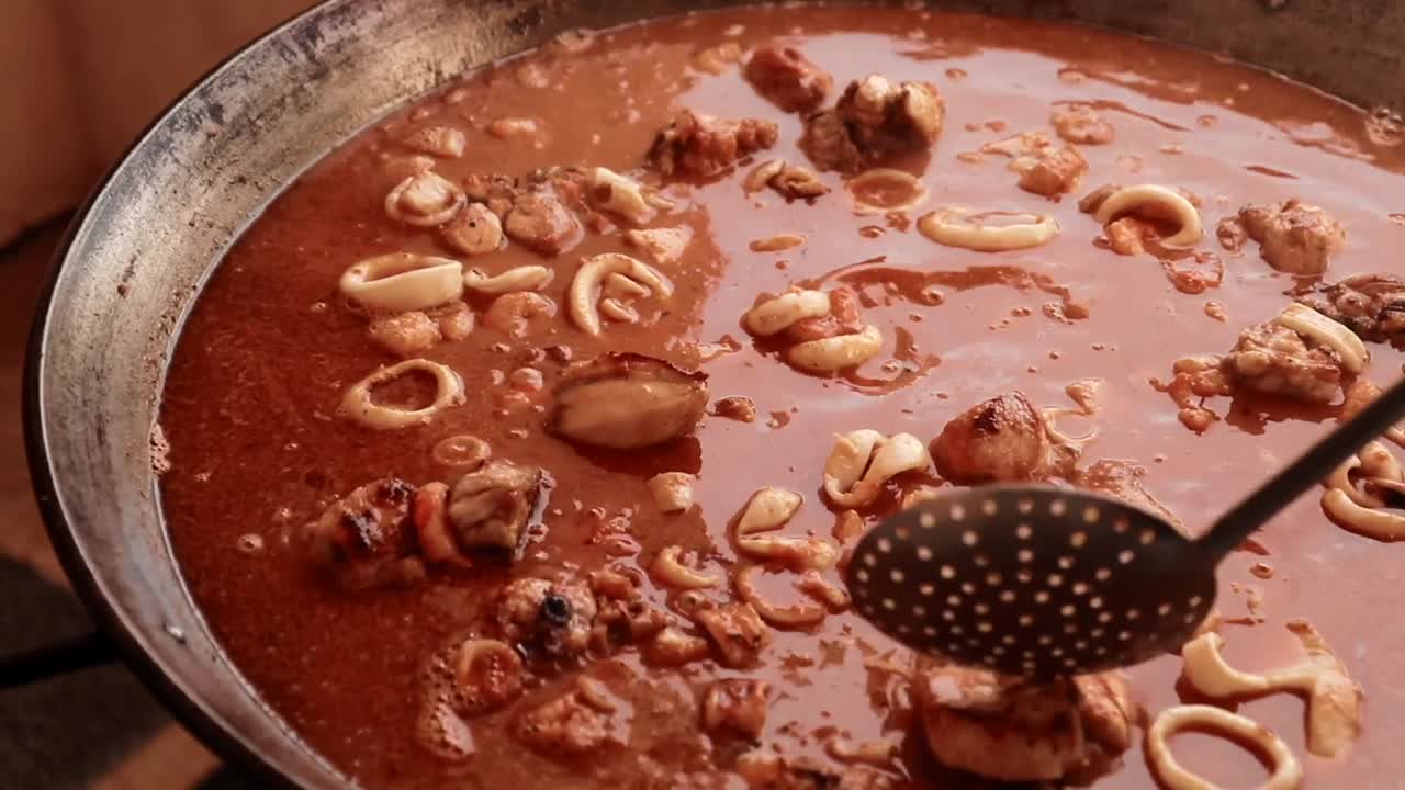 foto detallada de cómo un cocinero mueve los ingredientes de una paella, plato tradicional español.