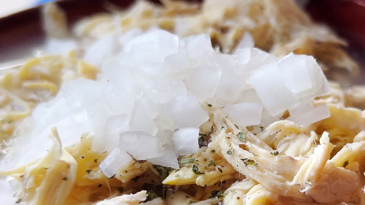 Chicken pozole featuring shredded chicken simmered in smoky chipotle tomato sauce, serving as a flavorful option for tacos, tostadas, or enchiladas in Mexican cuisine