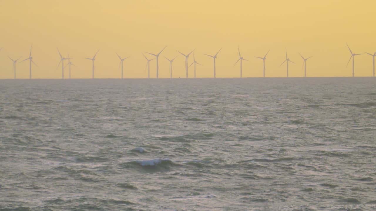Bright Slow Motion Wind Turbines Offshore Turning to Generate Power for Electricity. Net Zero Energy Targets with Green Sustainable Production. Offshore Power with Undersea Cables