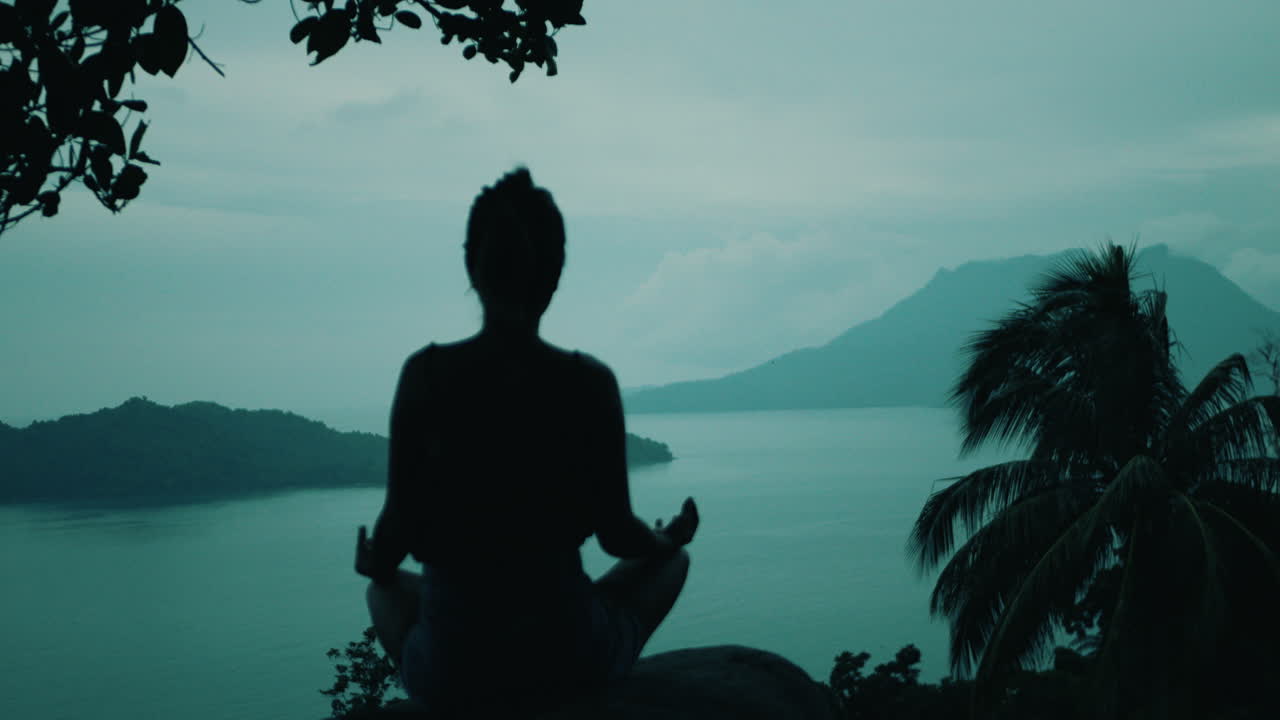 mujer meditando en un acantilado con vistas al océano