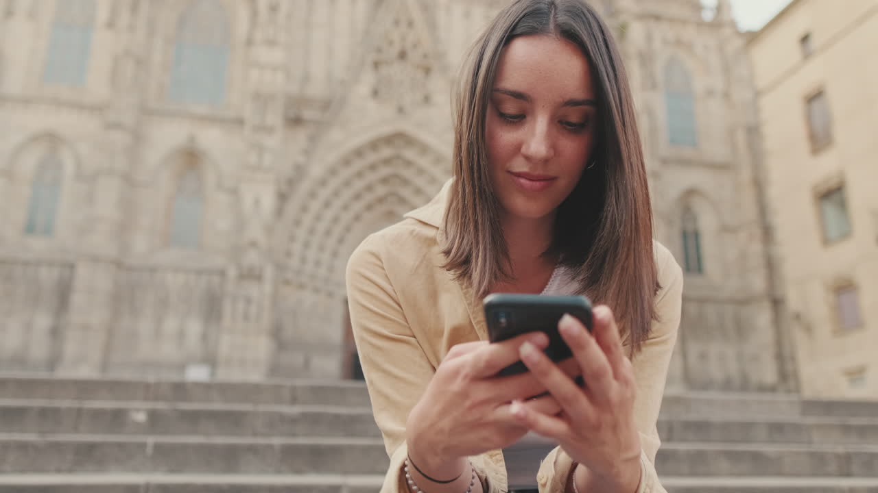 Giovane donna che usa lo smartphone all'aperto davanti a un edificio storico