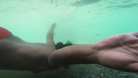 young diver exploring riverbed with pebbles under cold water of river with fish swimming