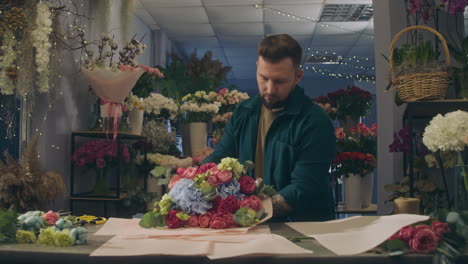 concentrated male florist wraps flowers bouquet