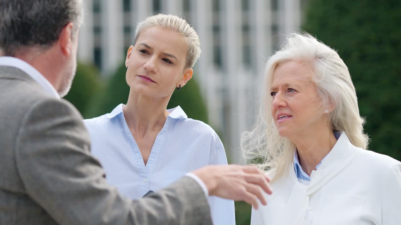 Three business professionals discussing content on a tablet during an outdoor meeting