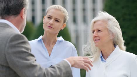 three business professionals discussing content on a tablet during an outdoor meeting