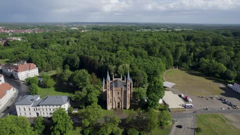 Drone-shot-of-Schlosskirche-church-in-green-forest-in-Neustrelitz,-Germany