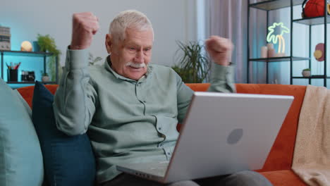 Grandfather-man-use-laptop-computer,-receive-good-news-message,-shocked-by-victory,-celebrate-win